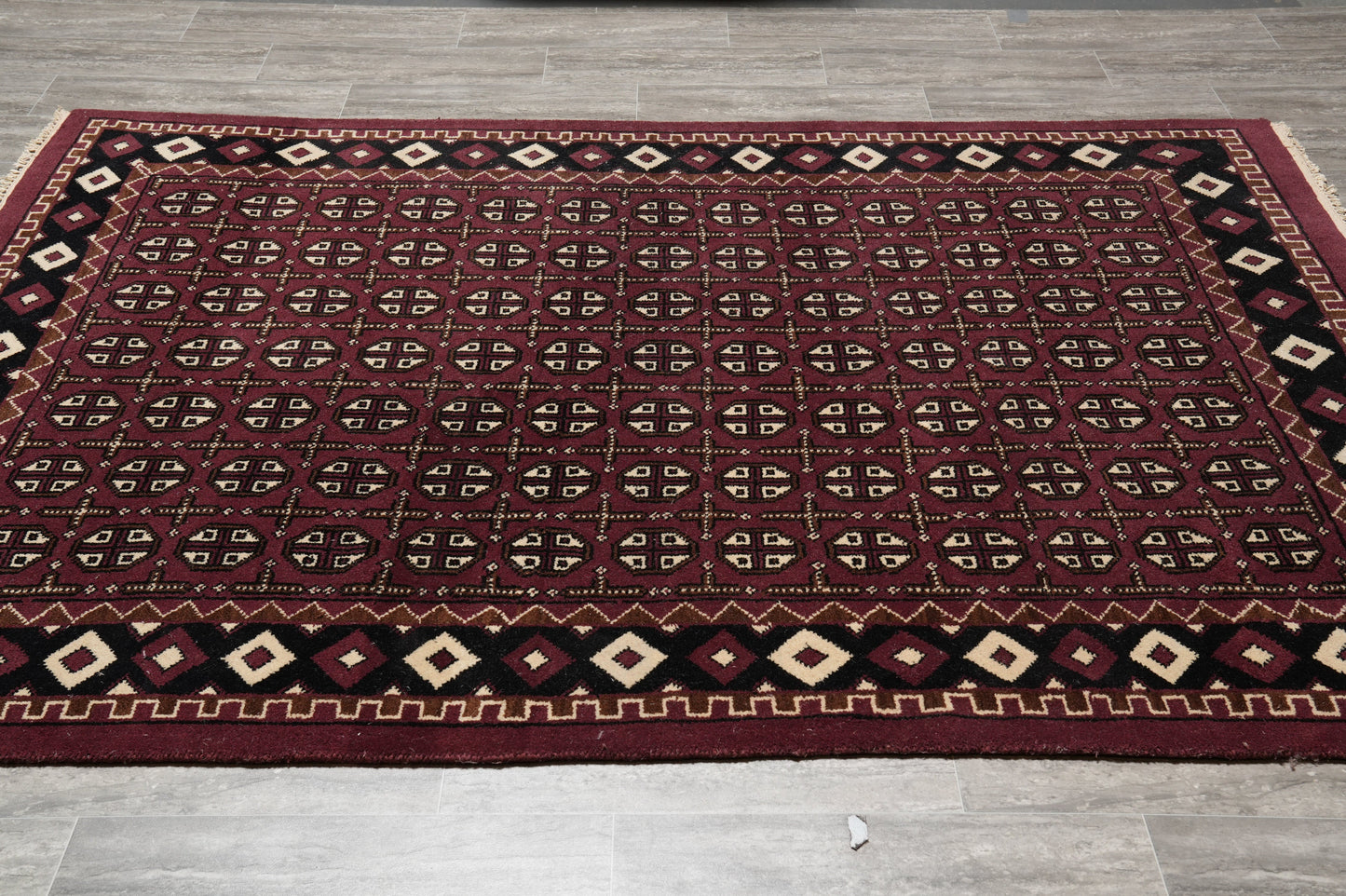 Turkman Bokhara burgundy rug, central gul medallion close-up on black field