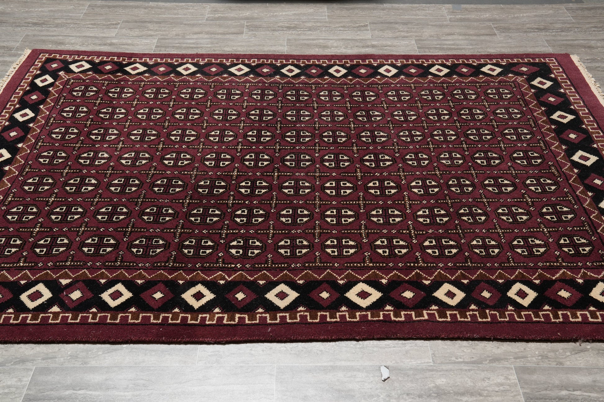 Turkman Bokhara burgundy rug, central gul medallion close-up on black field