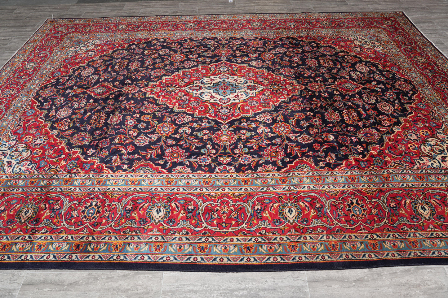 Signed Kashan-style navy rug, curvilinear floral detail in red and ivory