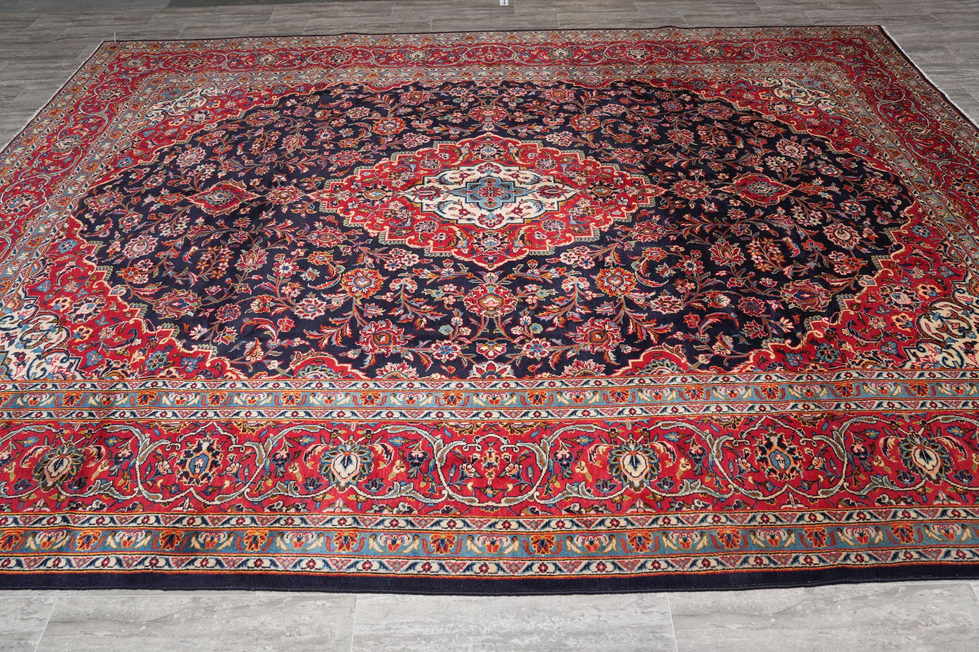 Signed Kashan-style navy rug, curvilinear floral detail in red and ivory