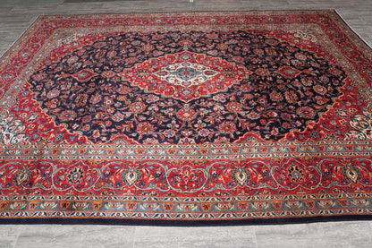 Signed Kashan-style navy rug, curvilinear floral detail in red and ivory