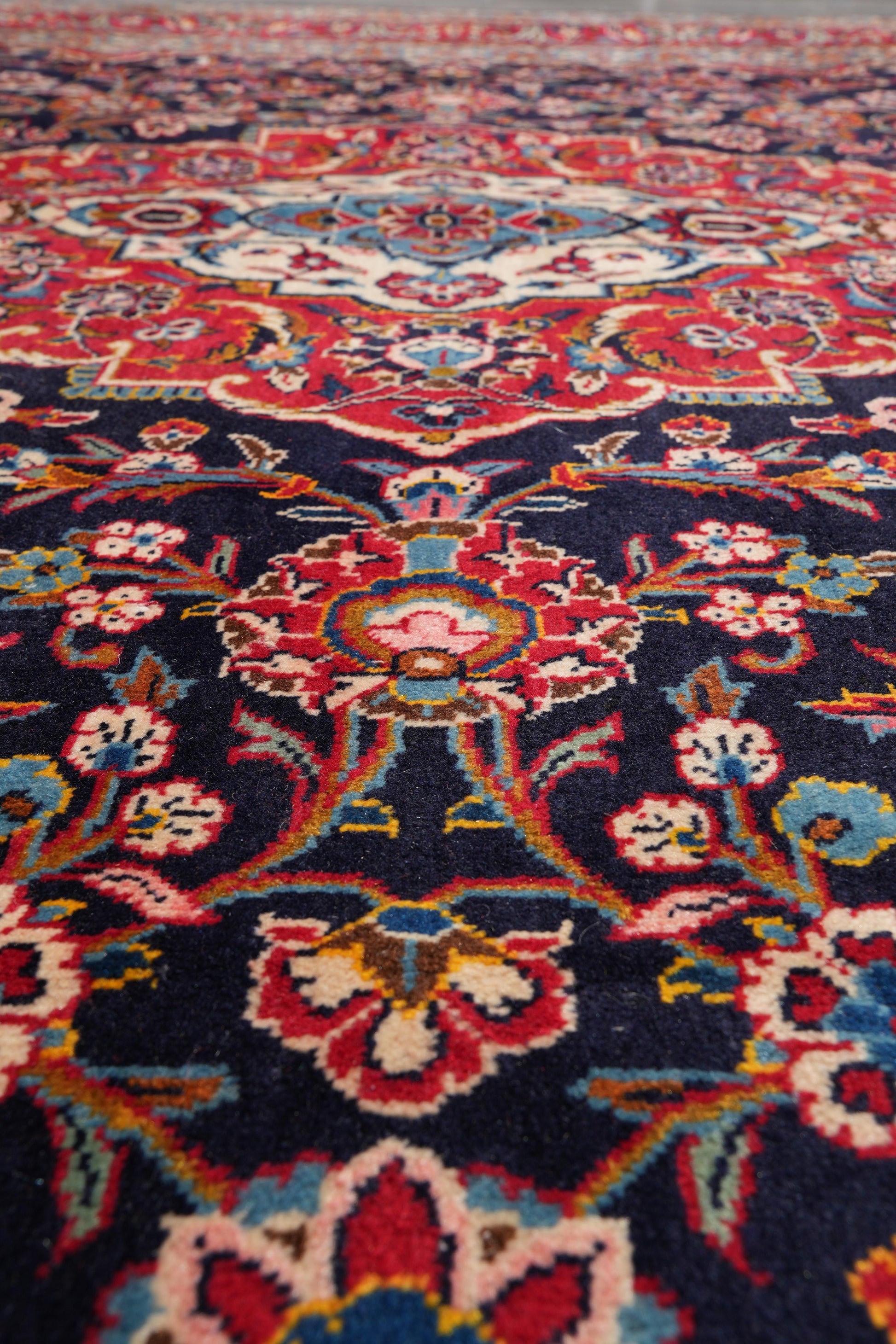 Signed Kashan-style navy rug, alternate corner with floral continuity