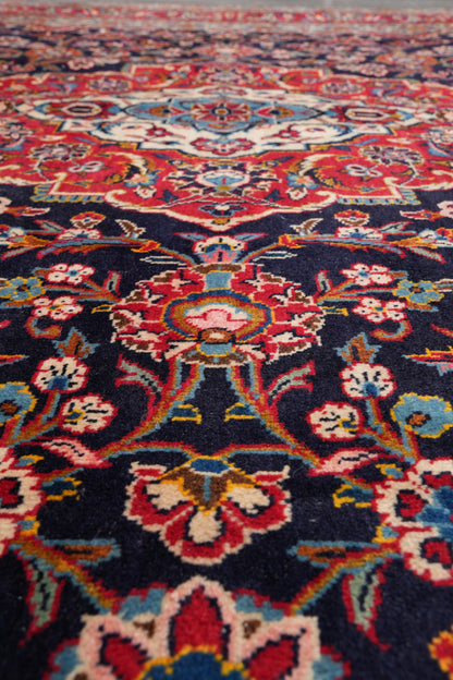 Signed Kashan-style navy rug, alternate corner with floral continuity